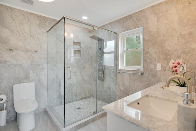 bathroom featuring toilet, a shower with door, vanity, and tile walls