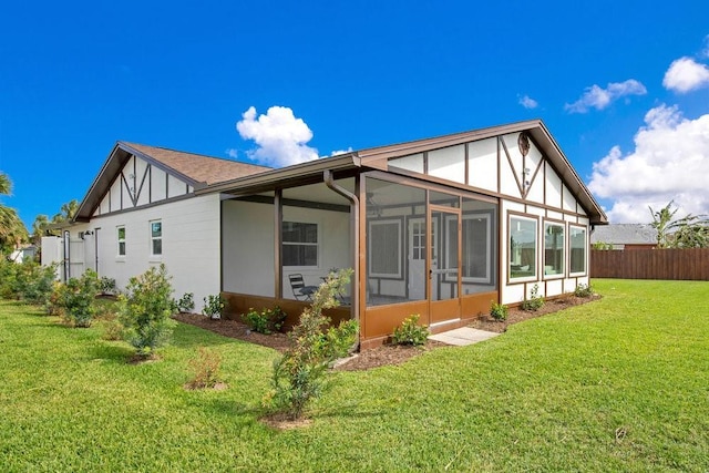 rear view of property featuring a lawn and a sunroom