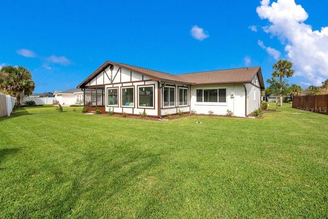 rear view of house with a lawn and a sunroom