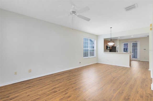 unfurnished living room with ceiling fan, wood-type flooring, and french doors