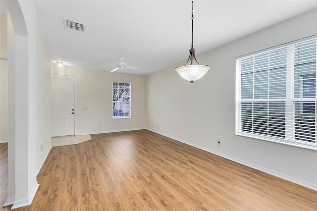 unfurnished room featuring ceiling fan, a healthy amount of sunlight, and wood-type flooring