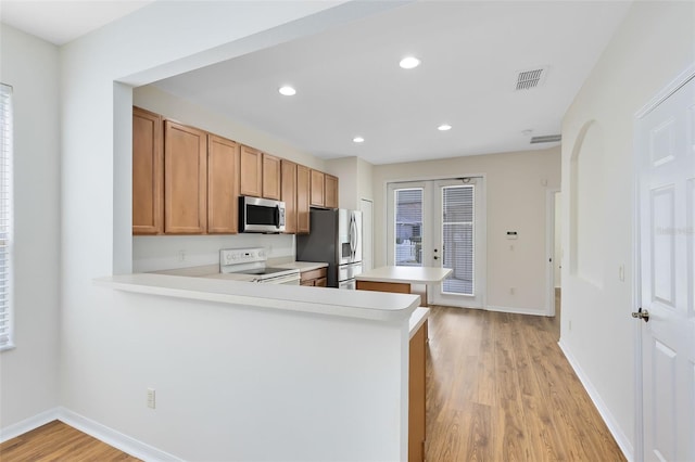 kitchen with kitchen peninsula, appliances with stainless steel finishes, and light hardwood / wood-style floors