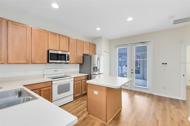 kitchen with a kitchen island, sink, light hardwood / wood-style flooring, stainless steel appliances, and french doors