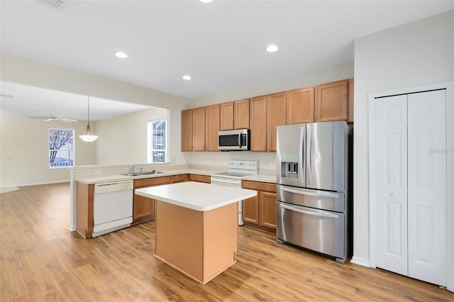 kitchen featuring kitchen peninsula, light wood-type flooring, stainless steel appliances, and hanging light fixtures