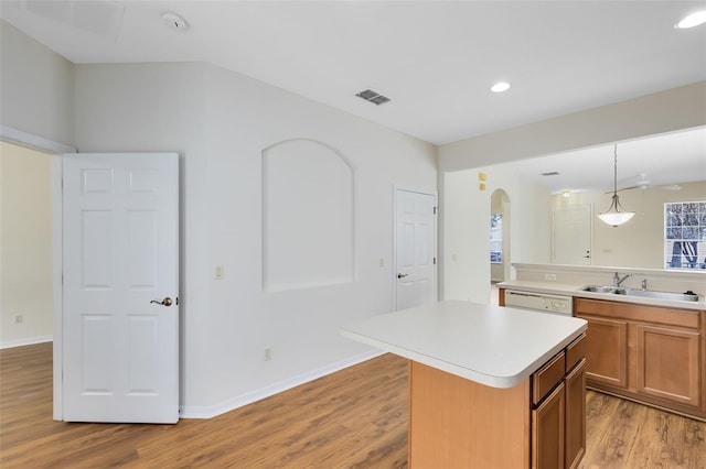 kitchen featuring pendant lighting, a kitchen island, sink, white dishwasher, and light hardwood / wood-style flooring