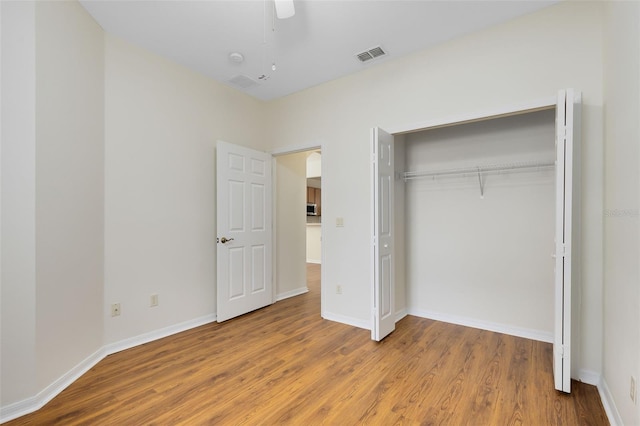 unfurnished bedroom with ceiling fan, hardwood / wood-style flooring, and a closet