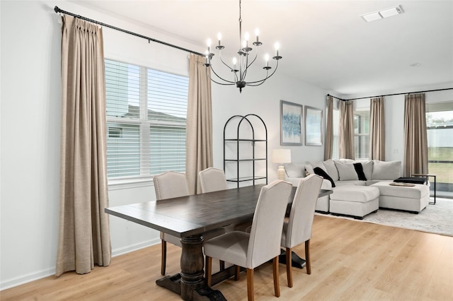 dining space with light hardwood / wood-style flooring, a notable chandelier, and a healthy amount of sunlight