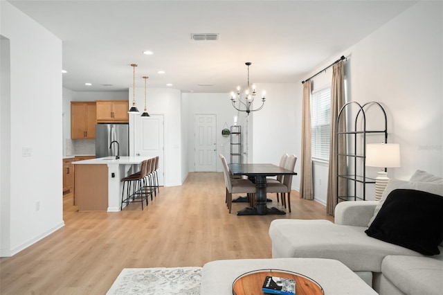 living room featuring light wood-type flooring, an inviting chandelier, and sink