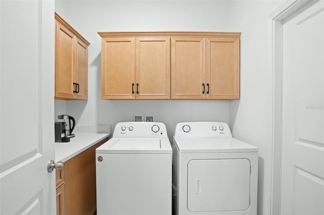 washroom featuring cabinets and washer and clothes dryer