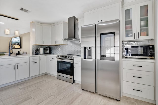 kitchen with stainless steel appliances, white cabinets, tasteful backsplash, and wall chimney exhaust hood