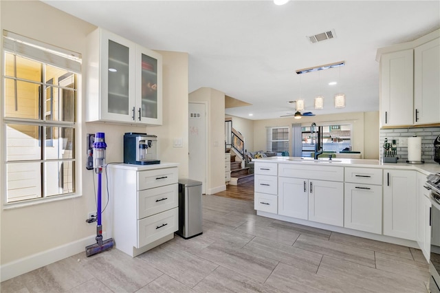 kitchen with white cabinetry, ceiling fan, kitchen peninsula, backsplash, and pendant lighting