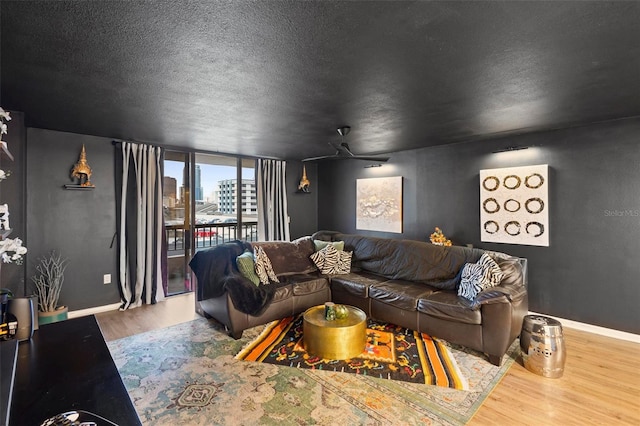 living area featuring a view of city, a ceiling fan, a textured ceiling, wood finished floors, and baseboards