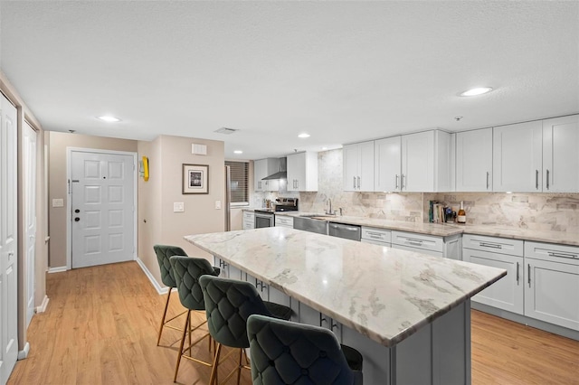 kitchen featuring stainless steel appliances, a breakfast bar area, white cabinets, and a center island