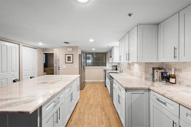 kitchen with stainless steel appliances, white cabinetry, and light stone countertops