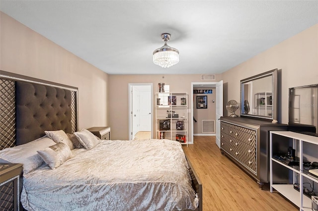 bedroom featuring light wood finished floors, visible vents, and a chandelier