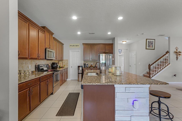 kitchen featuring appliances with stainless steel finishes, a breakfast bar, sink, backsplash, and a spacious island