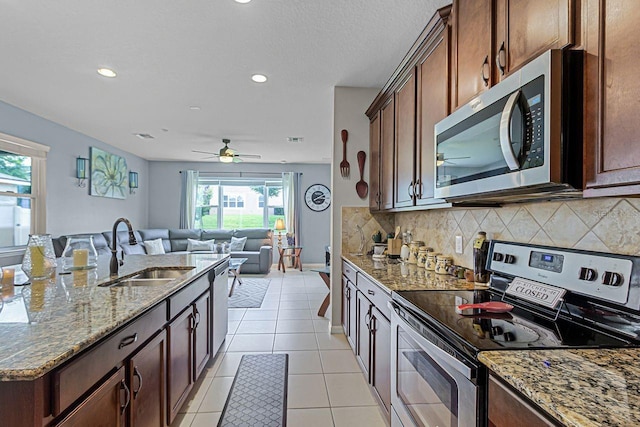 kitchen featuring appliances with stainless steel finishes, sink, decorative backsplash, light tile patterned floors, and light stone countertops