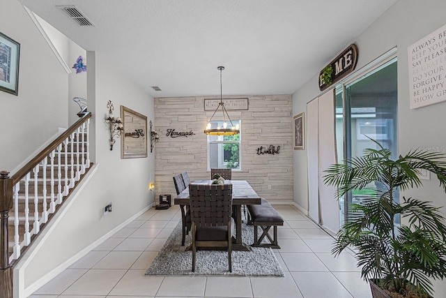 tiled dining space with a textured ceiling and a notable chandelier