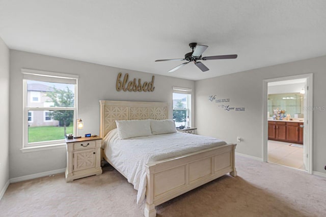 bedroom with ceiling fan, light carpet, and ensuite bath