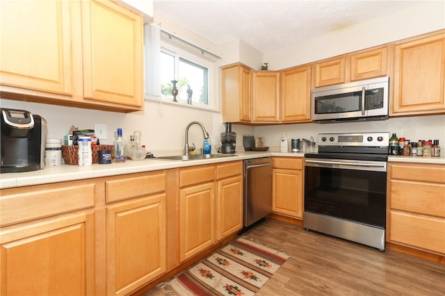 kitchen featuring sink, hardwood / wood-style floors, appliances with stainless steel finishes, and light brown cabinets