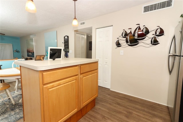 kitchen with a textured ceiling, stainless steel refrigerator, a kitchen island, pendant lighting, and dark wood-type flooring