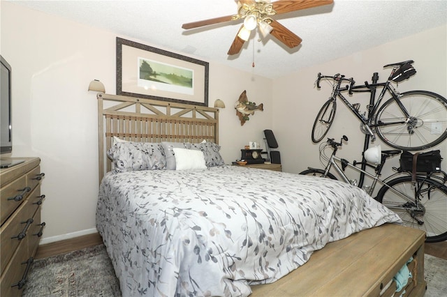 bedroom with ceiling fan, a textured ceiling, and dark hardwood / wood-style flooring