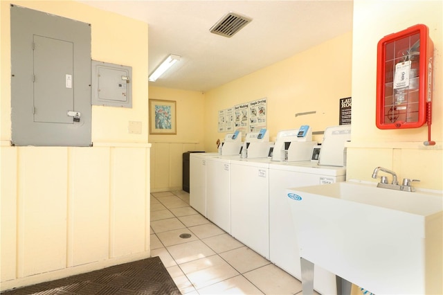 laundry area with sink, washing machine and clothes dryer, electric panel, and light tile patterned floors