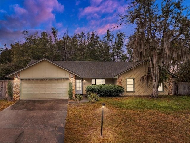 single story home featuring a garage and a lawn