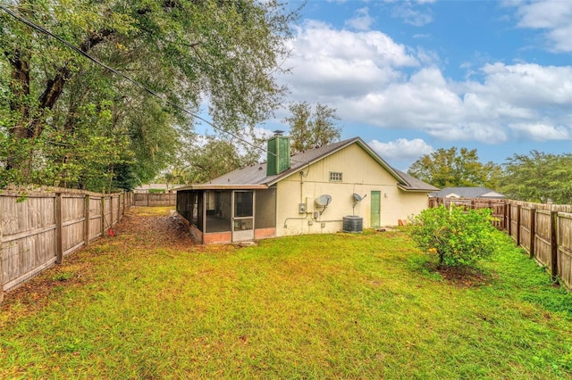 rear view of property featuring central AC, a sunroom, and a yard