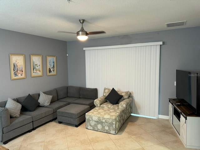 living room with ceiling fan, light tile patterned floors, and a textured ceiling