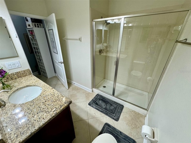 bathroom featuring toilet, tile patterned floors, vanity, and a shower with shower door