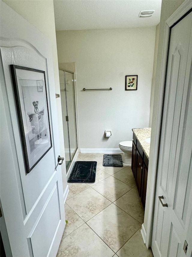 bathroom with walk in shower, vanity, tile patterned floors, and toilet