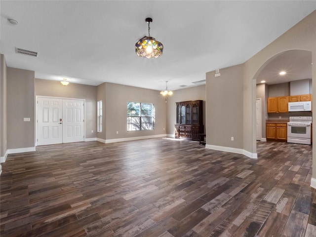 unfurnished living room with a notable chandelier and dark hardwood / wood-style floors