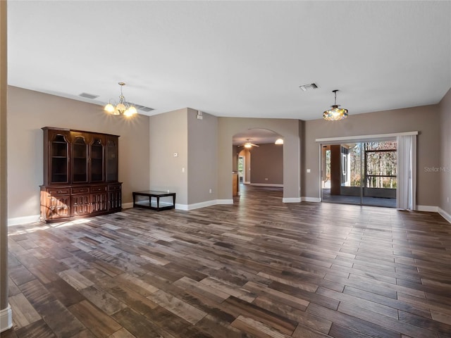 unfurnished living room with ceiling fan with notable chandelier and dark hardwood / wood-style floors