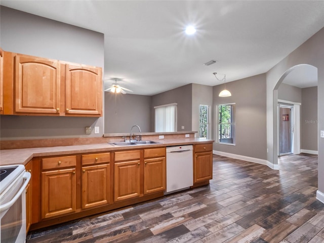 kitchen featuring white appliances, kitchen peninsula, decorative light fixtures, dark hardwood / wood-style flooring, and sink