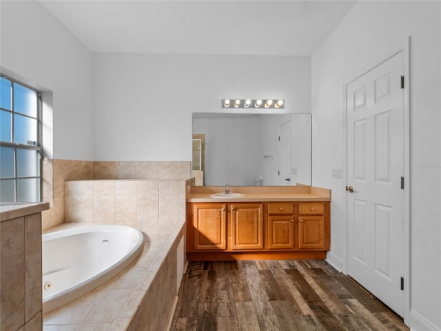 bathroom with tiled bath and vanity