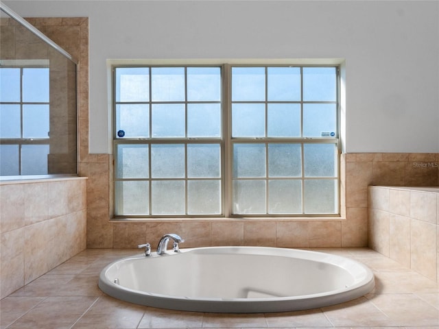 bathroom with a relaxing tiled tub and plenty of natural light