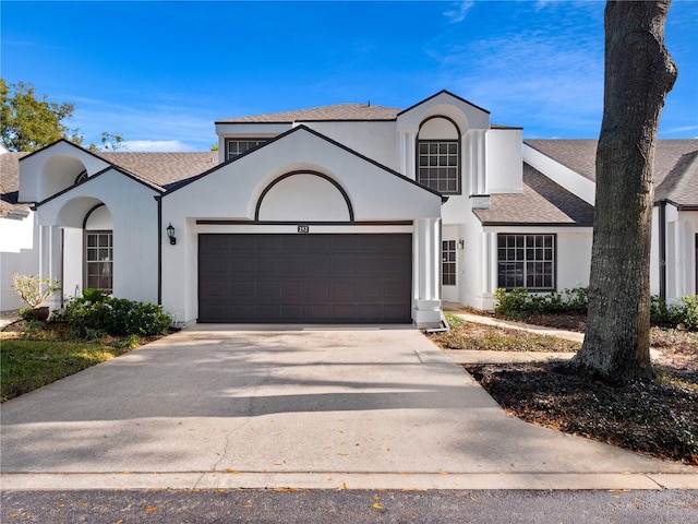 view of front facade featuring a shingled roof, concrete driveway, an attached garage, and stucco siding