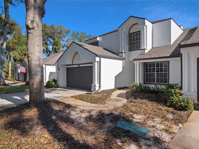 view of front of property featuring a garage, driveway, a shingled roof, and stucco siding