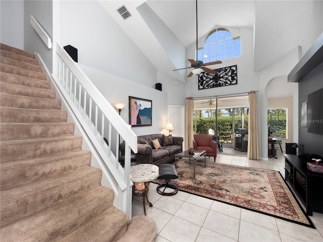 living area with arched walkways, light tile patterned floors, visible vents, stairway, and ceiling fan