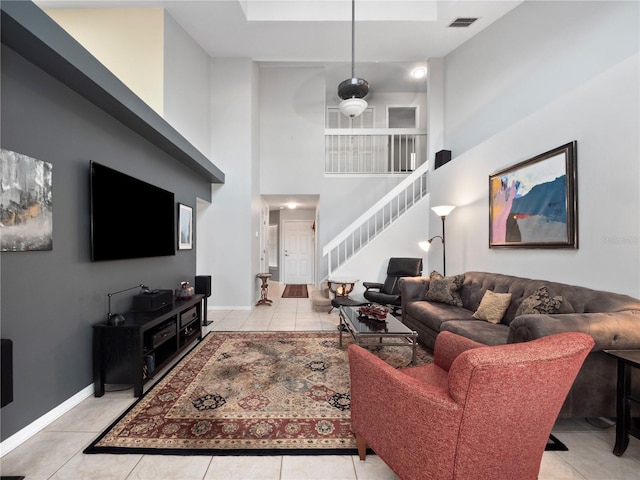 living room with light tile patterned floors, stairway, visible vents, and baseboards