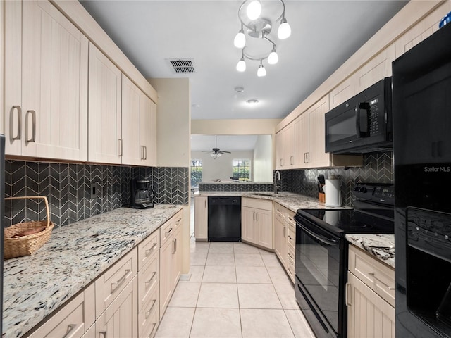 kitchen featuring black appliances, visible vents, light stone counters, and a sink