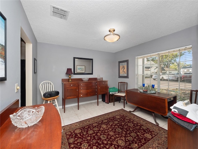 office space featuring light tile patterned floors, visible vents, and a textured ceiling