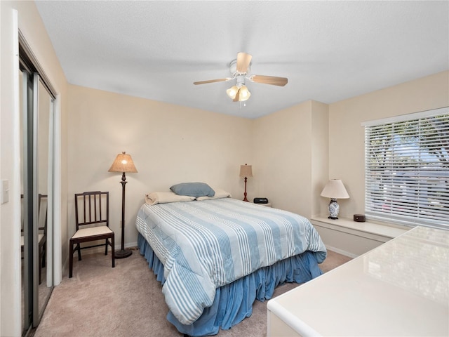 bedroom featuring a closet, light colored carpet, ceiling fan, and baseboards