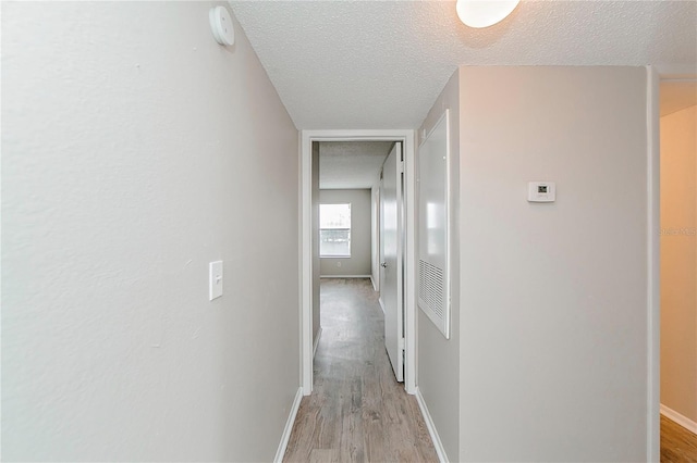 hallway featuring light hardwood / wood-style floors and a textured ceiling