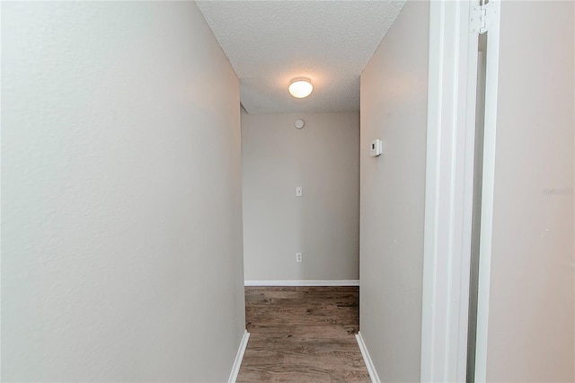 corridor with a textured ceiling and hardwood / wood-style flooring