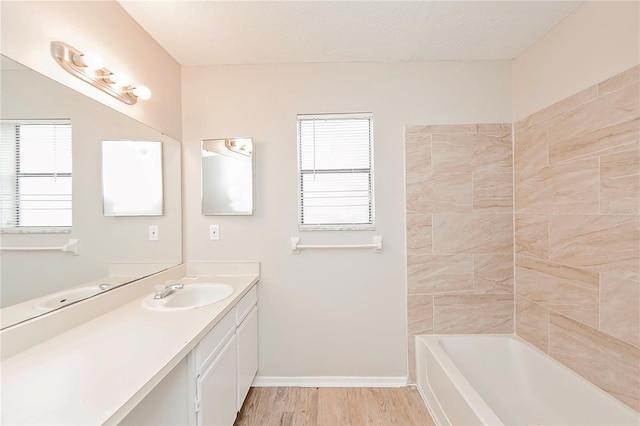 bathroom with a bathtub, a wealth of natural light, vanity, and hardwood / wood-style flooring