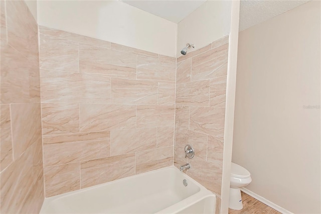 bathroom featuring toilet, a textured ceiling, tiled shower / bath, and hardwood / wood-style floors