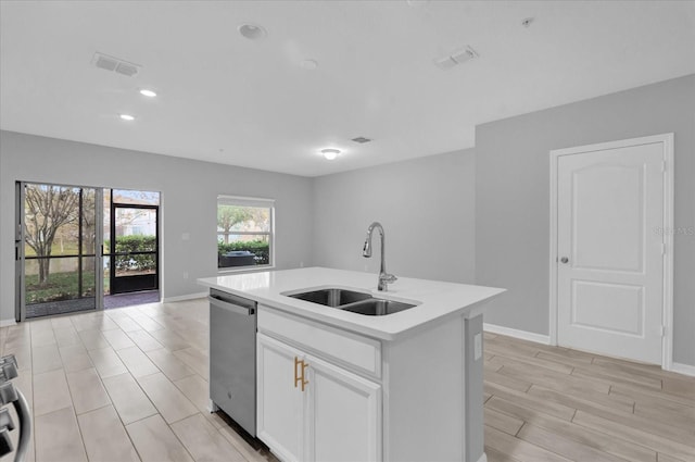 kitchen with stainless steel dishwasher, an island with sink, sink, and white cabinetry