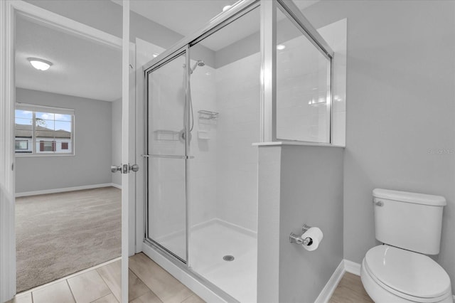 bathroom featuring toilet, tile patterned floors, and a shower with door